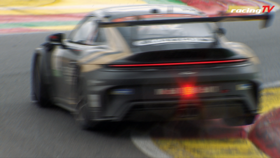Blurred gray race car seen from the rear speeding along a race track, with a large rear wing and red taillight strip in motion blur.