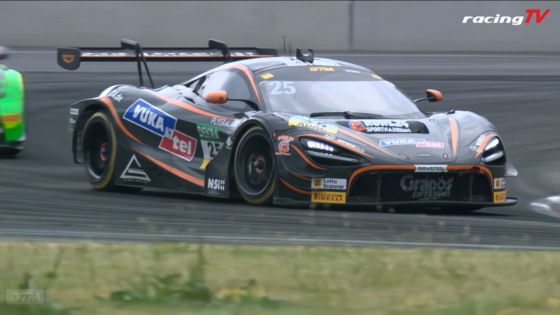 Grey race car with orange accents and sponsor decals, number 25, speeding along a race track with a large rear wing visible in the background.