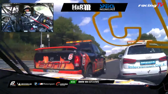In-car race view showing two cars ahead on a track with sponsor banners along the bottom and an inset cockpit image of the driver wearing a helmet.